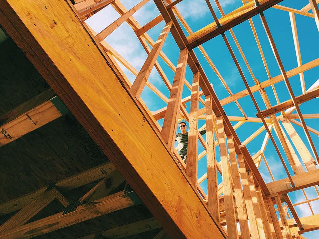 man looks down from second story of new house framing in Arizona