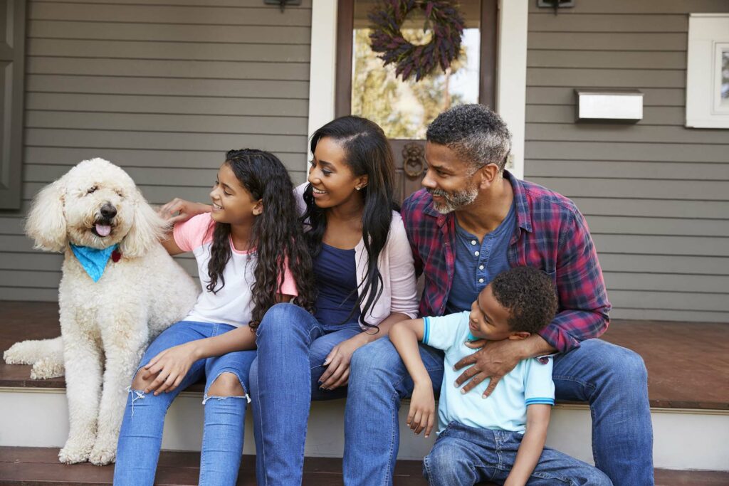 family and dog sit on porch steps of home in Prescott, AZ