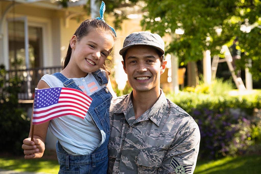 soldier holds young girl waving American flag in Prescott, Arizona