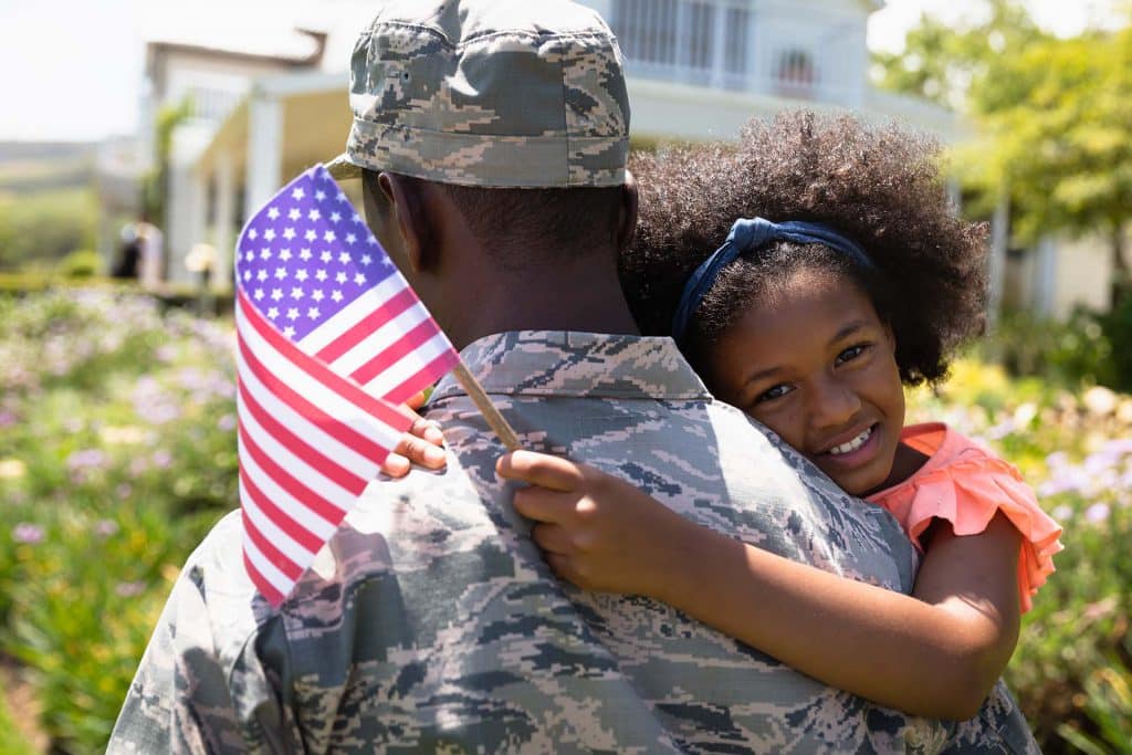 American soldier holding young girl holding flag